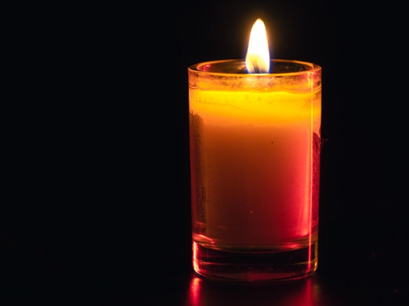 Burning candle on black background with backlight memorial day