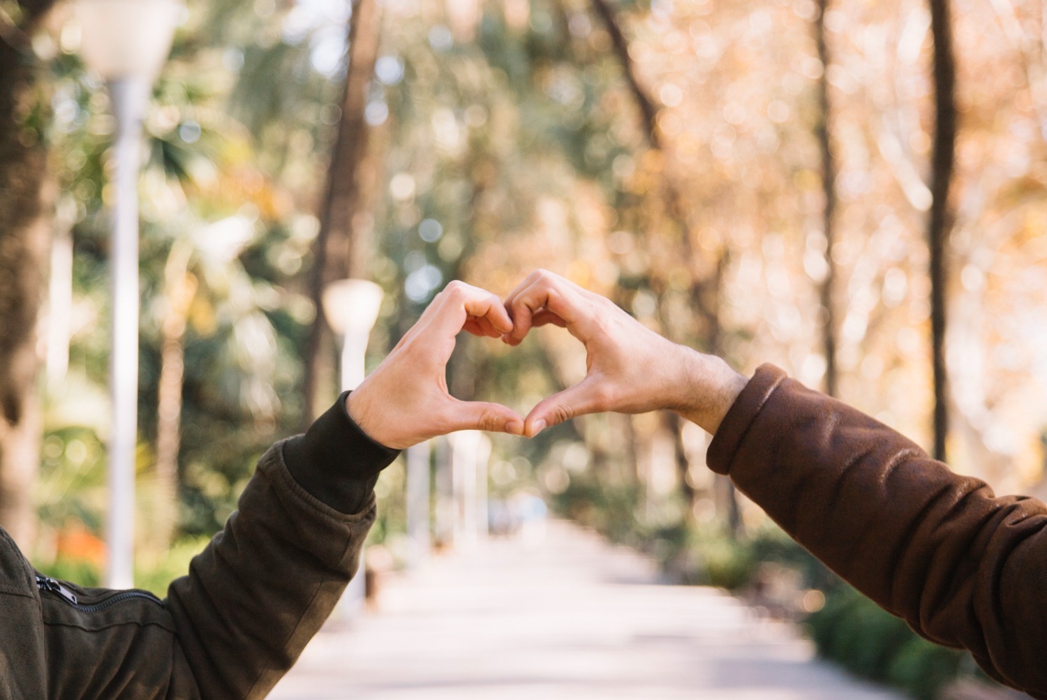 Crop men stacking hands showing hearts